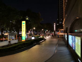 Illuminated street amidst buildings in city at night