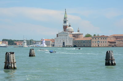 Boat in sea by buildings against sky