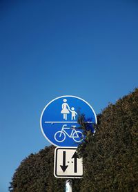 Low angle view of road sign against clear blue sky