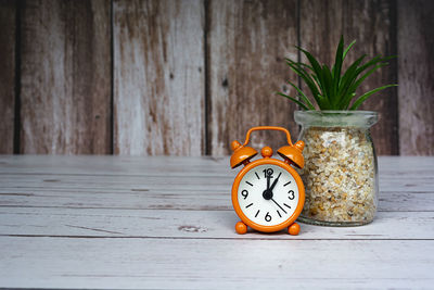 Orange alarm clock isolated on wooden desk. the clock set at 1 o'clock. deadline concept.