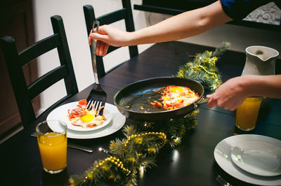 Midsection of woman serving food while standing by dining table at home