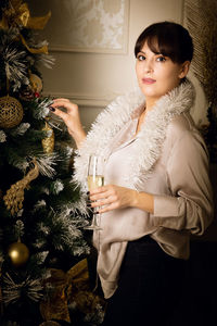 Portrait of young woman holding christmas tree