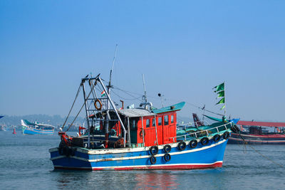 Boats in sea against clear blue sky