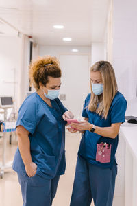 Mature nurse discussing with colleague using smart phone at hospital