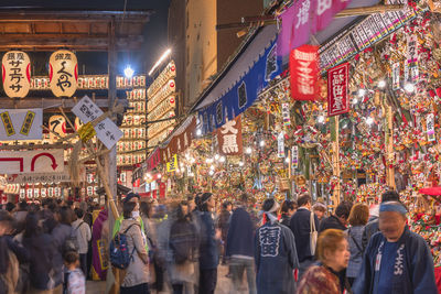 People walking on illuminated street in city at night