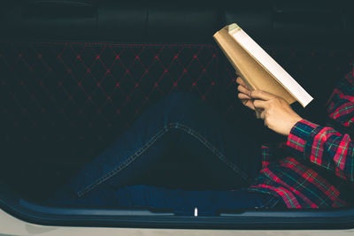 Midsection of woman reading book while sitting on seat