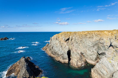 Rocks on sea shore against blue sky