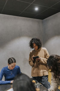 Businesswoman taking notes while discussing with female colleagues in creative office