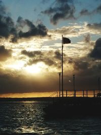 Silhouette of sea against cloudy sky during sunset