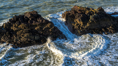 High angle view of waves splashing on rocks