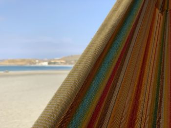 Close-up of multi colored umbrellas on beach against sky