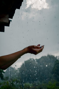 Hand holding wet glass during rainy season