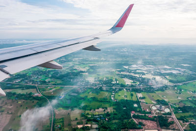 Aerial view of airplane flying over landscape against sky