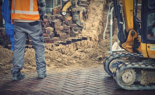 Low section of man standing by bulldozer at construction site