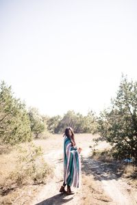 Rear view of young woman standing against clear sky