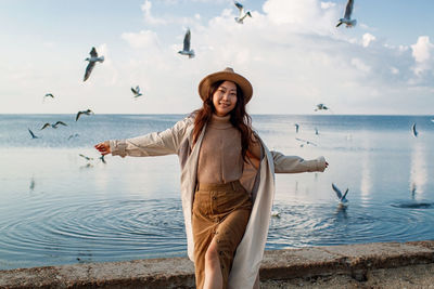 Happy asian girl on beach with flying birds in sky