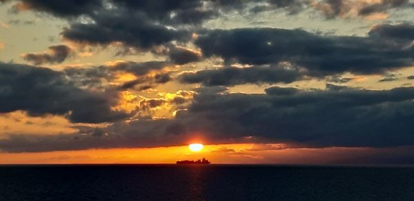 Scenic view of sea against dramatic sky during sunset