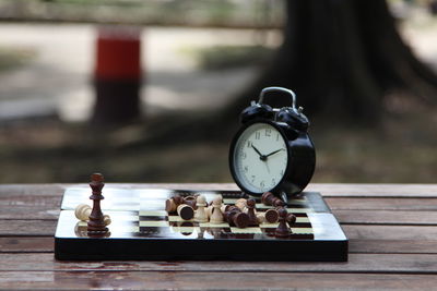 Close-up of clock with chess board on table