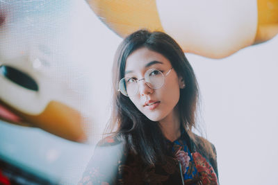 Portrait of young woman standing against illuminated city at night