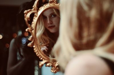 Close-up of woman looking at reflection in mirror