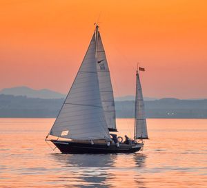 Sailboat sailing on sea against sky during sunset