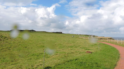 Scenic view of grassy field against cloudy sky