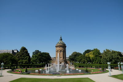 Fountain in park against clear blue sky