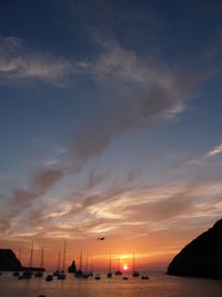 Silhouette of boats in sea at sunset