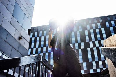 Low angle view of woman standing by modern buildings against sky