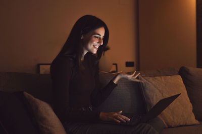 Young woman using laptop while sitting on sofa at home