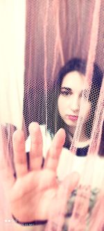 Close-up portrait of woman hiding behind curtain