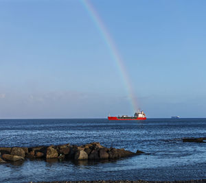 Scenic view of rainbow over sea against sky