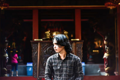 View of man looking away while sitting against temple