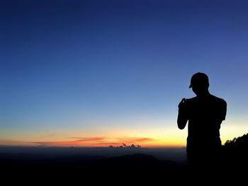 Silhouette man standing against sky during sunset