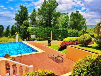 Swimming pool by trees against sky