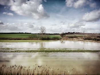 Scenic view of river against cloudy sky