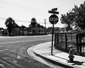 Road sign by street against sky