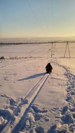Rear view of person on snow covered field against sky