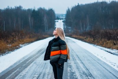 Woman standing on snow covered road
