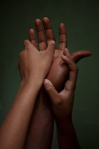 Cropped image of several hands touching each other on dark green background