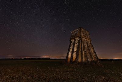 Built structure on field against sky at night