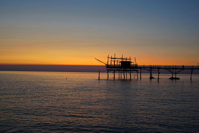 Silhouette ship in sea against sky during sunset