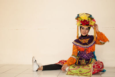 Portrait of woman sitting against wall