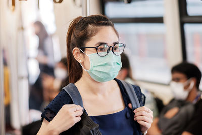 Close-up of woman wearing mask standing in train