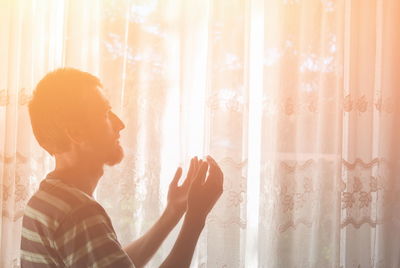 Side view of young man looking through window