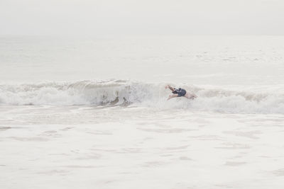 Man surfing in sea against sky