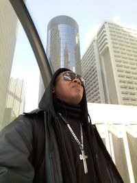 Low angle view of young man standing against buildings