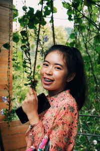 Portrait of smiling woman standing against plants