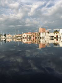 Buildings by lake against sky in city