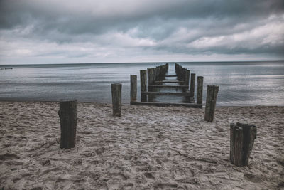 Wooden posts on beach against sky